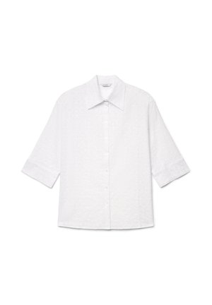 Blouse blanche boutonnée avec manches aux trois quarts, col pointu et motif floral subtil brodé sur un tissu léger.