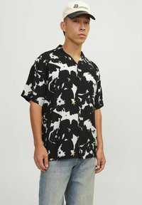 Kortærmet skjorte i sort og hvid med et blomstermønster med gule accenter. Knap-ned design. Casual pasform.