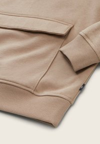 Beige sweatshirt met een ribgebreide onderkant en boorden, voorzien van een kangoeroezak en een gladde textuur. Minimalistisch ontwerp, geen zichtbare branding.