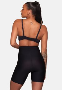 Svarta högmidjade shaping shorts gjorda av ett slätt, stretchigt material, med justerbara remmar och en sömlös design.