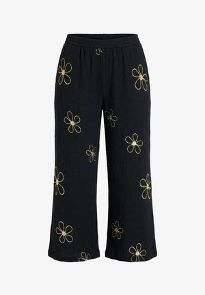 Czarne szerokie spodnie z elastycznym pasem i żółtymi haftowanymi wzorami stokrotek rozrzuconymi na materiale.
