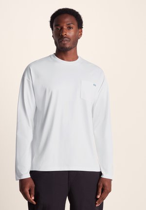 Long-sleeve white t-shirt made of smooth fabric, featuring a chest pocket with a small blue logo and a round neckline.