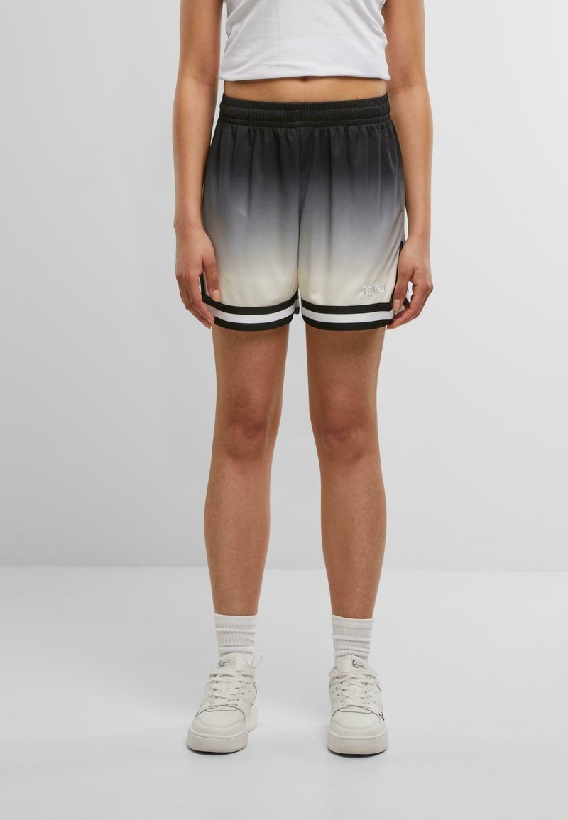Personne portant un short dégradé du noir au blanc avec deux bandes noires aux ourlets, des chaussettes blanches, des baskets blanches et un haut court blanc.