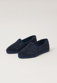 Navy suede slip-on shoes with a woven jute sole. Minimalist design features a smooth texture and no visible hardware or embellishments.
