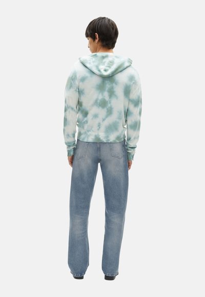 Sudadera con capucha en un patrón de tie-dye en azul claro y blanco, con un dobladillo y puños acanalados. Combinada con jeans rectos de color azul claro.