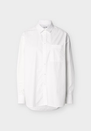 Valge pikkade varrukatega nööpidega särgi ees on tasku ja klassikaline krae, mis on esitatud ühevärvilisel heledal taustal.