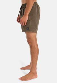 Hnědé plavky s elastickým pasem a šňůrkou na stažení, s malou nášivkou loga na levé straně. Hladký textilní materiál.