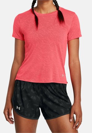 Kobieta ubrana w jaskraworóżową teksturowaną koszulkę z krótkim rękawem oraz czarne sportowe spodenki z subtelnym wzorem i logo Under Armour.