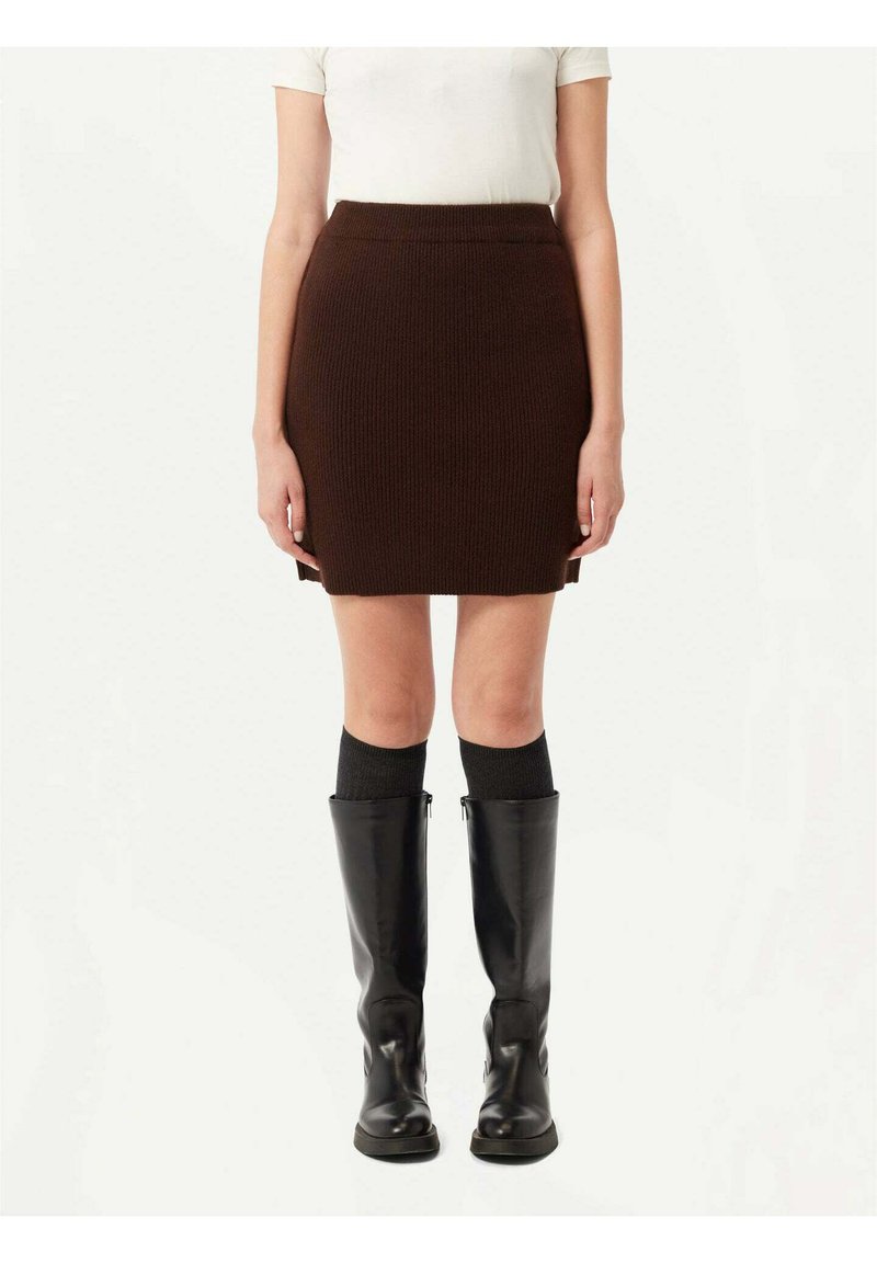 Brun stickad kjol med en figurnära design, med en ribbad textur. Kombinerad med knähöga svarta läderstövlar och ribbade svarta strumpor.