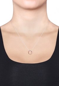Zilveren ketting met een ronde hanger. De hanger heeft een accent van roségoud. De achtergrond is een effen kleur, waardoor de ketting extra opvalt.