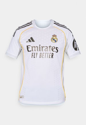 Maillot de football blanc à manches courtes, avec des accents noirs et jaunes, un col rond et un tissu texturé. Affiche le logo de l'équipe et le nom du sponsor.