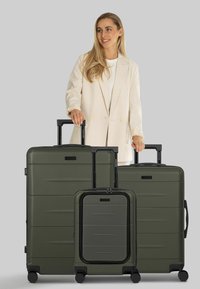 Set di valigie verde scuro in tre pezzi con finitura testurizzata, maniglie nere e ruote lisce. Le dimensioni variano dal piccolo bagaglio a mano alla valigia grande.