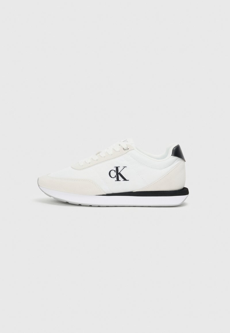Białe i jasnobeżowe sneakersy z gładką cholewką, zamszowymi akcentami, czarną osłoną pięty i białą podeszwą. Zawierają haftowane logo "ck".