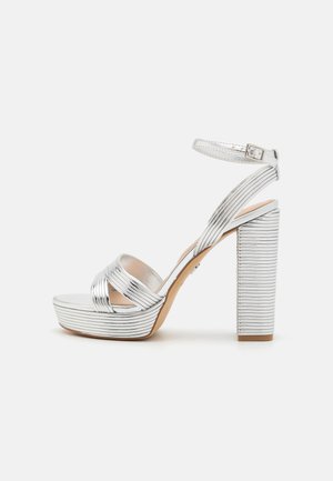 Zilveren sandalen met hoge hakken, voorzien van een ribbelstructuur, platformzool en verstelbare enkelband. De blokhak zorgt voor stabiliteit.