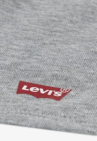 Γκρι πλεκτό ύφασμα που διαθέτει κόκκινη ετικέτα Levi's στην κάτω γωνία, με υφή μαλακή και ορατές ραφές.
