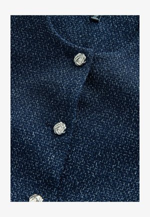 Cardigan bleumarin din țesătură cu textură, decorat cu nasturi argintii în formă de noduri în partea din față.