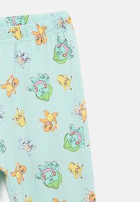 Helle blaue Leggings mit verschiedenen Cartoonfiguren. Aus weichem Stoff mit elastischem Taillenbund, der bunte Muster zeigt.