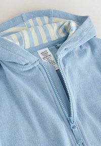 Lyseblå hættetrøje med lynlås i blødt, tekstureret stof. Stribet for i sarte farver, inkluderer mærkat med vaskeanvisninger.