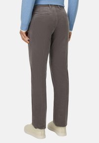 Pantalones de pana gris con un corte recto, que cuentan con una cinturilla plana, bolsillos traseros y tejido texturizado. Combinados con zapatillas de color claro.