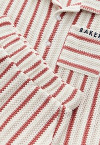 Indumento in maglia di cotone con un design a colletto, caratterizzato da strisce alternate crema e rosse, superficie testurizzata e chiusure con bottoni.