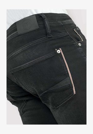 Zwarte denim jeans hebben een slim fit met twee achterzakken, een leren label op de tailleband en contrasterende stiksels langs de zaknaden.