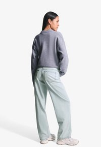 Grijze cropped sweater met een ronde halslijn, gecombineerd met lichtblauwe wijdvallende jeans. Kenmerkt zich door een relaxte pasvorm en zachte, textuurvolle stof.