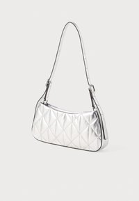 Quiltelt ezüst kézitáska sima, ívelt formával és állítható vállpánttal, fényes fémes bevonattal és diszkrét varrási részletekkel.