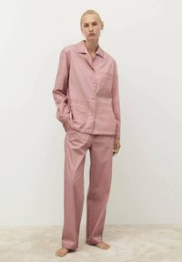 Rosa pyjamasett som innehåller en skjorta med knappar och en ficka, samt matchande byxor med en lös passform och ett mjukt, strukturerat tyg.
