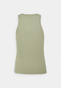 Zielony prążkowany top na ramiączkach o dopasowanym kroju, z zaokrąglonym dekoltem i teksturowaną tkaniną. Brak widocznych wzorów lub elementów metalowych.