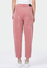 Roze corduroy broek met een ontspannen pasvorm, voorzien van een gestructureerde oppervlakte, twee achterzakken en een elastische tailleband. Geaccentueerd met een zwart label.