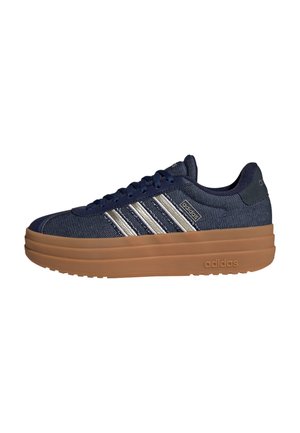 Navy blue Adidas sneaker with tan thick sole, white three stripes on side, and Adidas logo near heel and tongue.