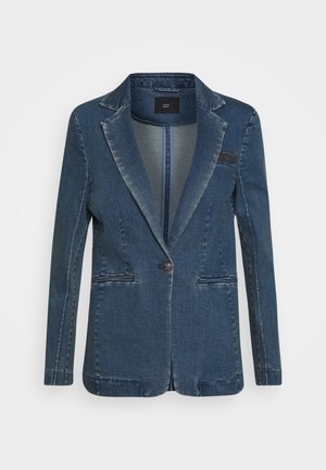 Blazer en denim bleu avec un bouton unique, des revers crantés et deux poches passepoilées à l'avant, présenté sur un fond blanc.