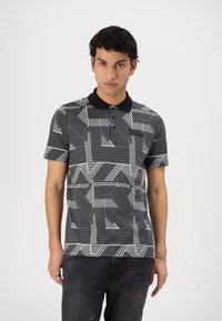 Polo de manga corta en blanco y negro con patrones geométricos. Presenta un cuello negro y una tapeta de tres botones. Material de mezcla de algodón.