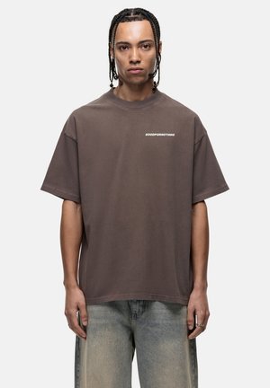T-shirt ample marron en coton doux avec un col rond et des manches courtes ; comporte l'inscription "GOODFORNOTHING" imprimée en blanc sur la poitrine.