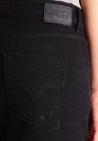 Schwarze Jeans aus Denim mit einer Gesäßtasche, die einen dezenten Used-Look aufweist, und einem Lederlogo-Patch am Bund. Schlichtes Design und sichere Nähte.