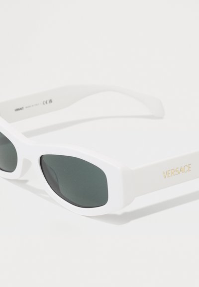 Valged ülisuured päikeseprillid roheliste läätsede ja paksude raamidega, mille templil on kuldne "VERSACE" logo. Sile viimistlus ja nurkadega disain.