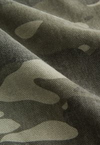 Material de camuflaj în nuanțe de verde, cu un finisaj texturat și țesut; prezintă forme aleatorii în model și o senzație moale, durabilă.