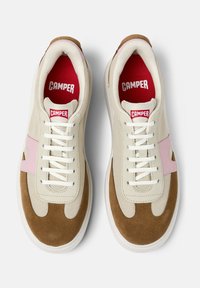Beige und braune Sneaker mit pinkem Akzent und weißen Schnürsenkeln, die das "Camper"-Logo in Rot auf der Innenseite und der Zunge tragen.
