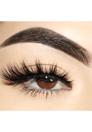 Brown eye with long, black false eyelashes and defined dark eyebrow, against a light beige background, highlighting eye detail and texture.
