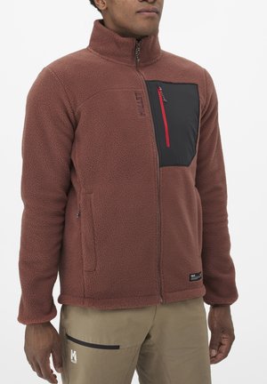 Brown fleece jacket with a high collar, a black chest pocket with red zipper, and side pockets. Features a textured, soft fabric.