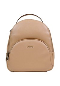 Beige läderryggsäck med rundad form, framficka med dragkedja, dubbla blixtlås och en metallisk logotyp. Axelremmar och ett handtag upptill för bärning.