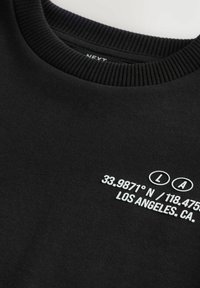 Svart sweatshirt med ribbat rundhals. Har vit text som visar koordinater och "LA" på framsidan. Gjord av mjukt tyg.