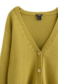 Grön stickad cardigan med V-ringning, två knappar och ribbad krage. Texturerad tyg med synliga sömmönster.