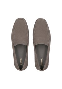 Mocassini in suede grigi con design piatto, caratterizzati da dettagli cuciti e una fodera interna liscia. Il logo del marchio è stampato in oro all'interno.