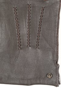 Leren handschoen in donkerbruin met decoratieve stiksels en contrasterend garen. Bevat een metalen logo-accent en een gladde textuur.