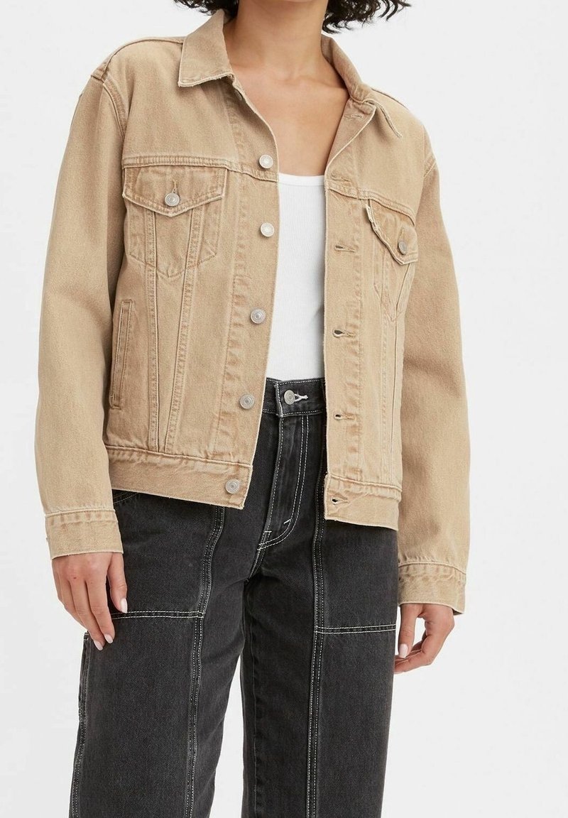 Giacca in denim beige con colletto standard, patta con bottoni e tasche sul petto. Presenta un design classico e una vestibilità rilassata.