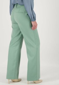 Wijde mintgroene broek met een soepele textuur, uitgerust met achterzakken en een klassieke pasvorm, gecombineerd met een lichtblauwe blouse.