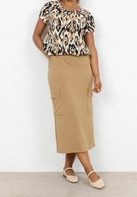 Short-sleeve top with a multi-colored animal print design, paired with a beige, knee-length skirt featuring two large front pockets.