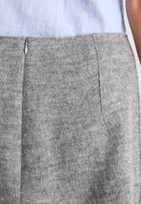 Jupe en tissu gris avec une texture lisse, une fermeture éclair latérale et un design simple et épuré sans motifs ni accents visibles.