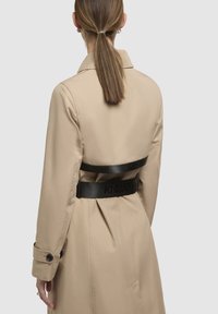 Beige trench coat with a black belt. Features a classic collar, fold details on the back, and buttoned cuffs. Smooth texture, minimalistic design.